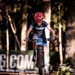 Ungdomar i 13–14-årsåldern cyklar i ett XCO-lopp på en skogsbana med kurvor och lättare hinder.