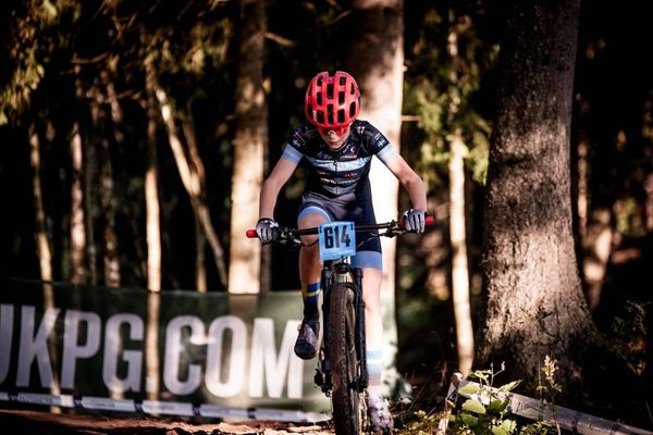 Ungdomar i 13–14-årsåldern cyklar i ett XCO-lopp på en skogsbana med kurvor och lättare hinder.